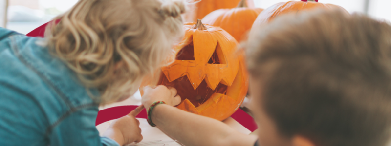 Two children carving pumpkins.
